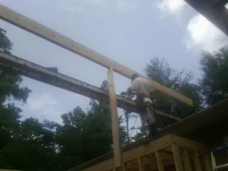 Carpenter setting a ridge beam over a new addition frame — Ice Dam Removal by Roofing Brothers in Ellington