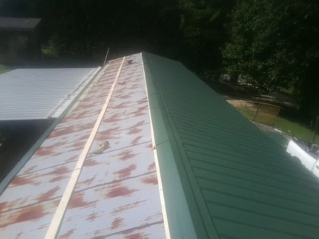 Old rusted panels beside newly installed green metal roofing — Wind Damage Roof Repair by Roofing Brothers in Ellington