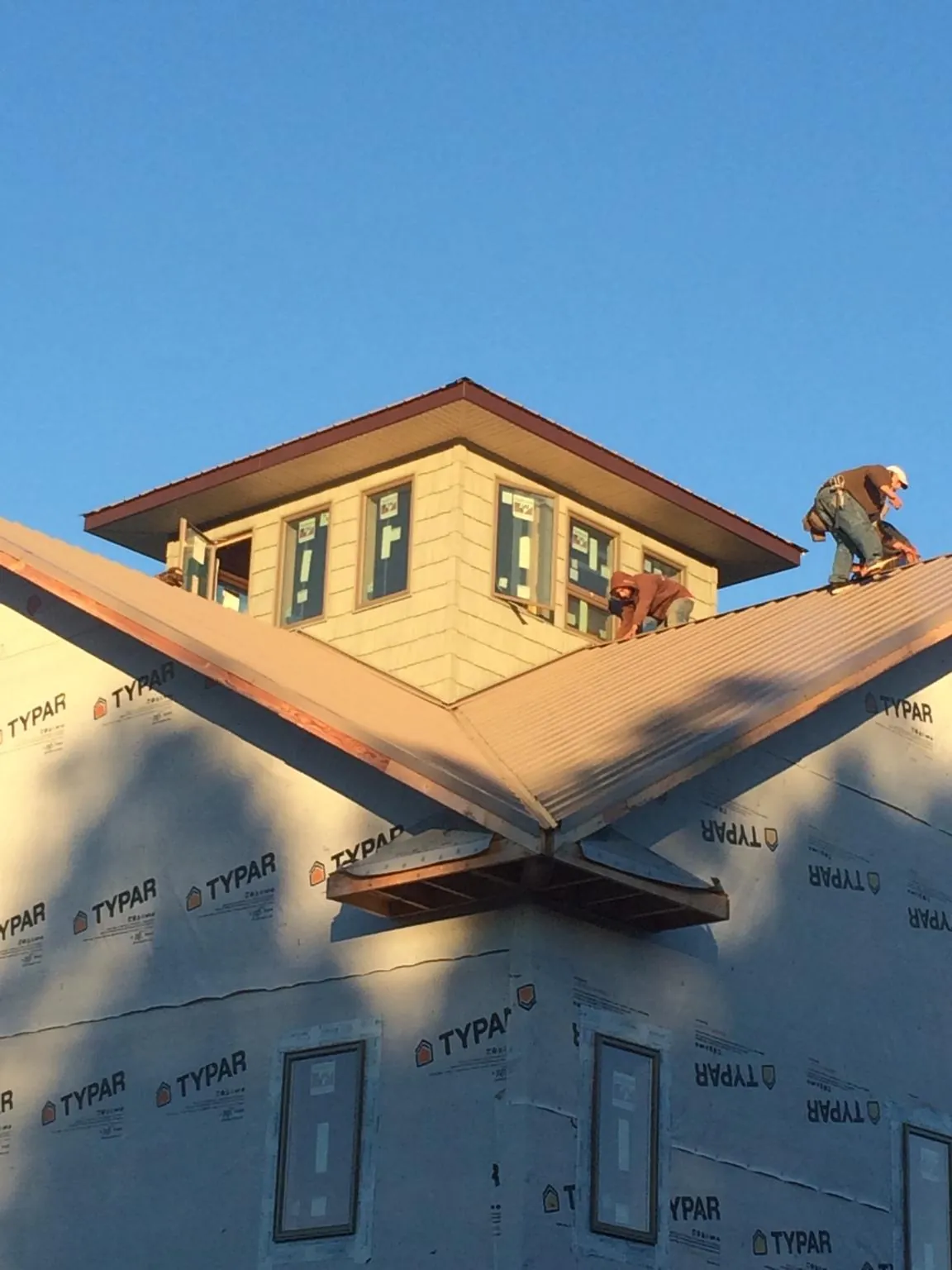 Roofers working around a rooftop cupola on a new metal roof at sunset — Roof Waterproofing in Ellington by Roofing Brothers